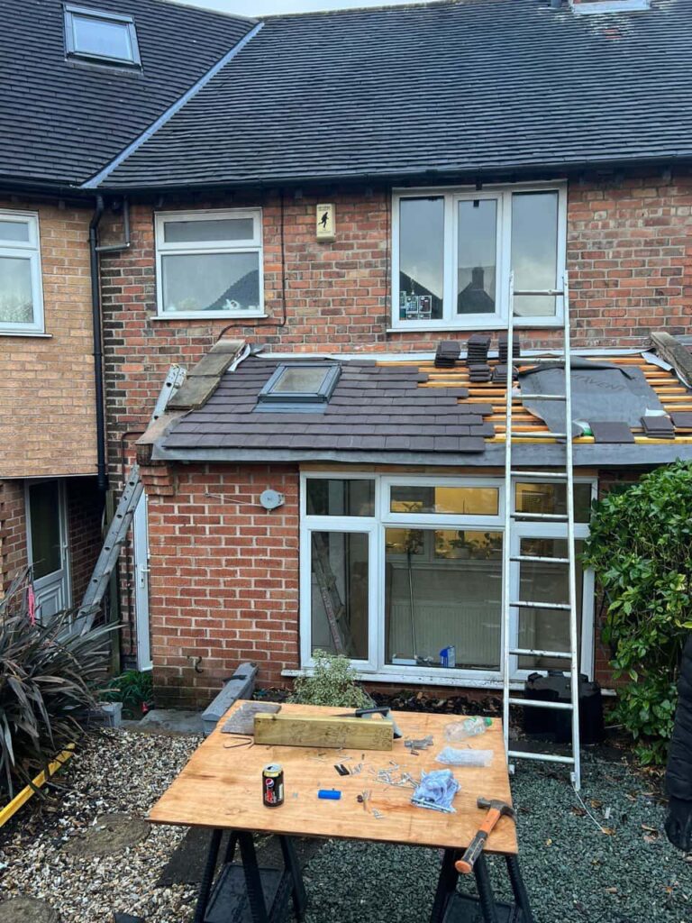 This is a photo of a roof extension that is having new roof tiles installed. This is a photo taken from the roof ridge looking down a tiled pitched roof on to a flat roof. Works carried out by March Roofing Repairs