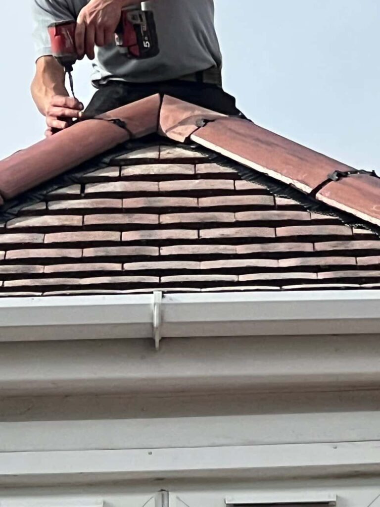 This is a photo of one of the operatives of March Roofing Repairs installing new ridge tiles